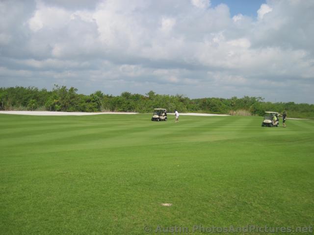 Golfers and golf carts on a fairway at Playa Mujeres golf course.jpg