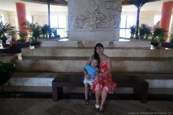 Darwin held by mommy sitting on bench in front of monolithic sculpture at Grand Bahia Principe Tulum lobby.jpg